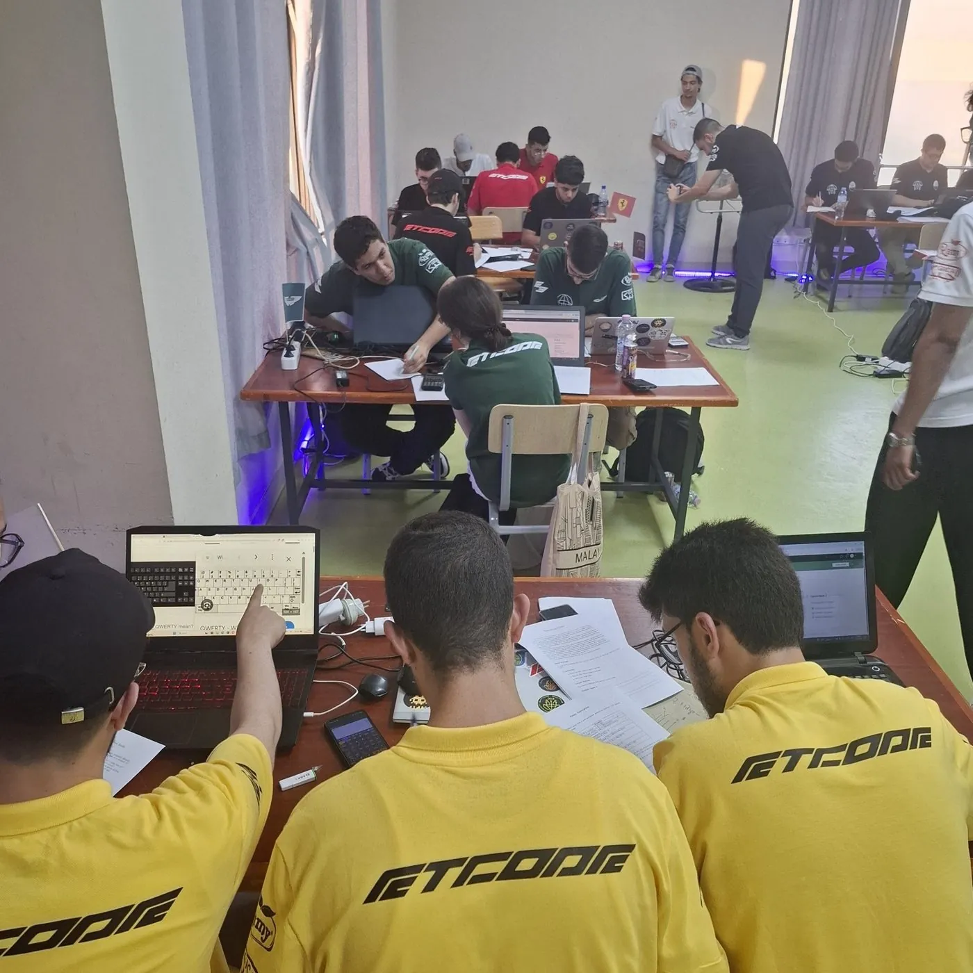 A team in yellow ETCode shirts working at their table